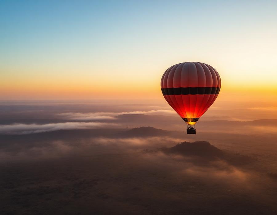 Hot air balloon drifting over the misty Maasai Mara at sunrise